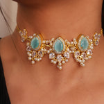 Load image into Gallery viewer, Close-up of a gold necklace with turquoise stones and pearl accents on a person wearing a black top.