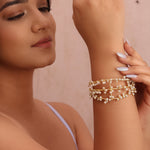 Load image into Gallery viewer, Woman wearing multiple gold bracelets on her wrist against a beige background