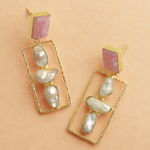 Load image into Gallery viewer, Gold earrings with pink and white stones on a beige background
