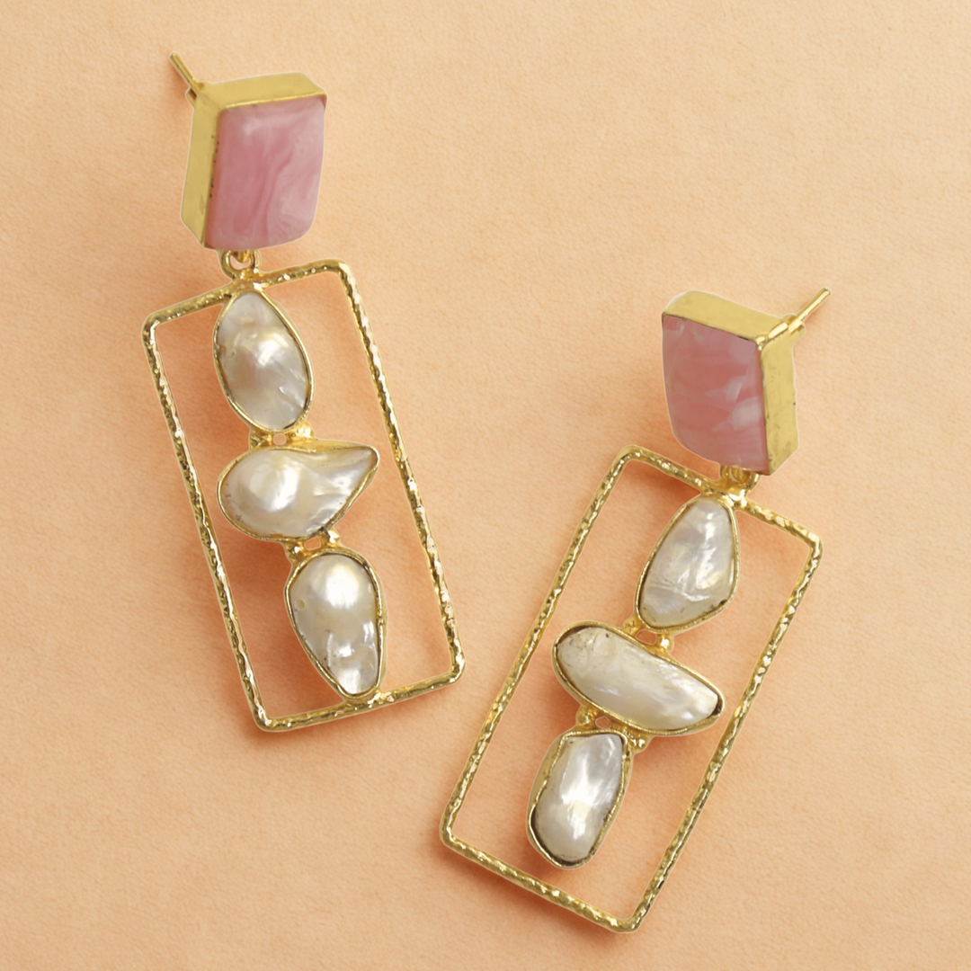 Gold earrings with pink and white stones on a beige background