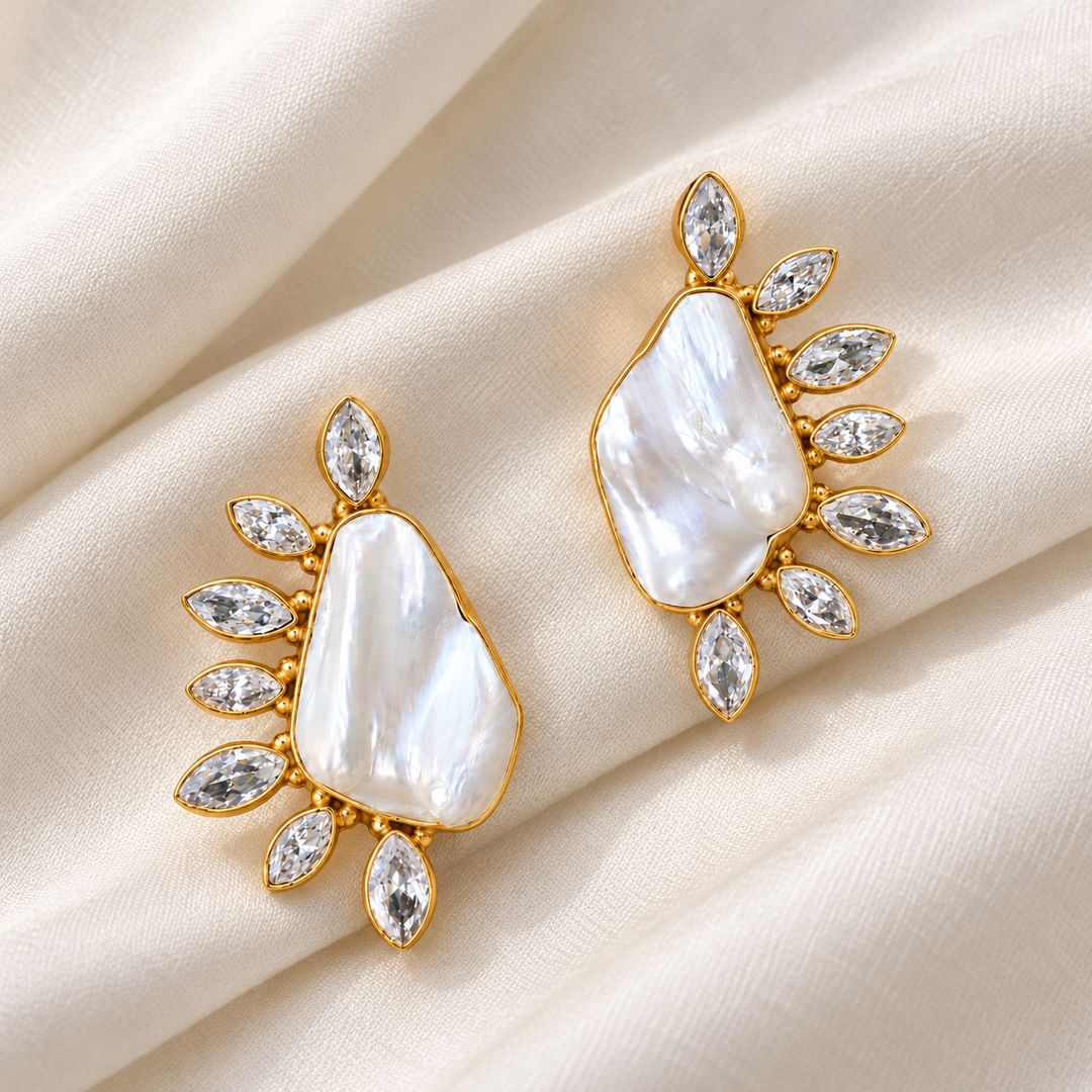 Baroque pearl and cubic zirconia leaf-frame stud earrings arranged diagonally on ivory silk