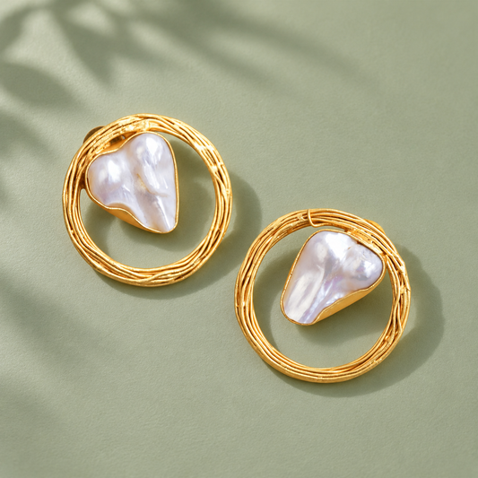 Baroque pearl woven-circle stud earrings on a sage-green surface