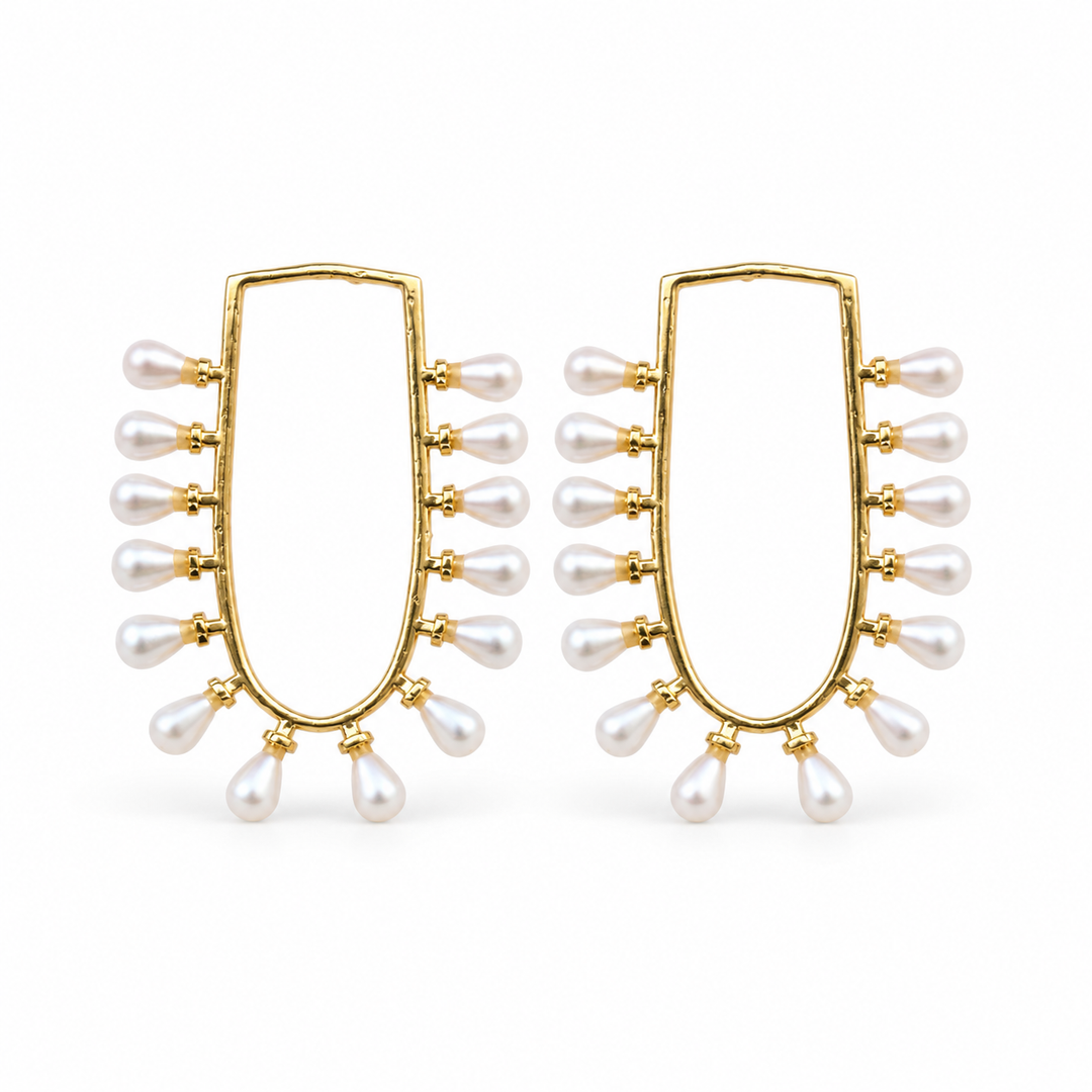 Gold-tone U-frame earrings edged with white teardrop pearl accents on white