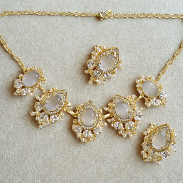 Gold jewelry set with necklace and earrings on a light gray background